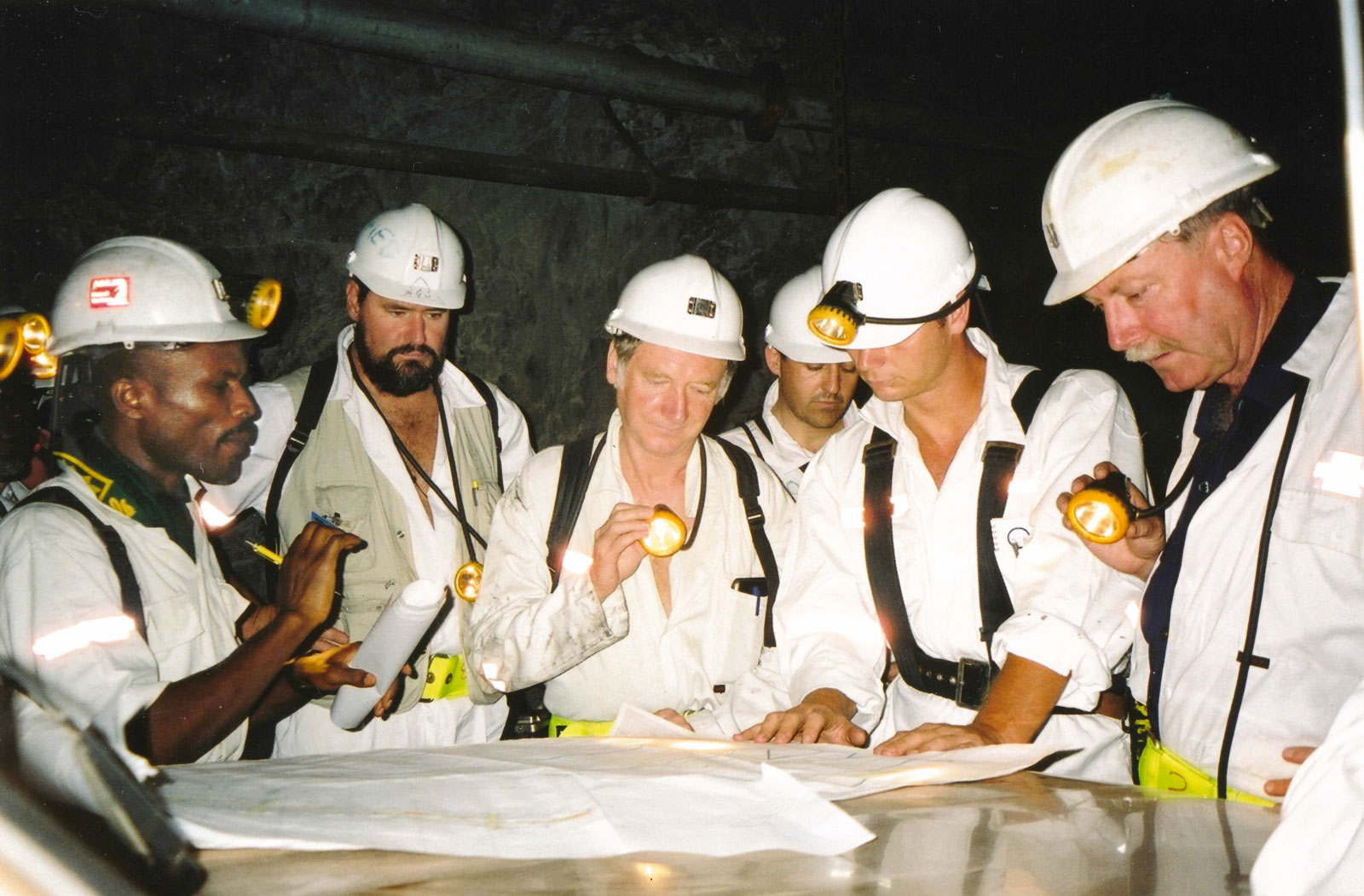 Ashanti Goldfields staff explain the orebody over plans on a Toyota bonnet, underground at Obuasi, Ghana.
